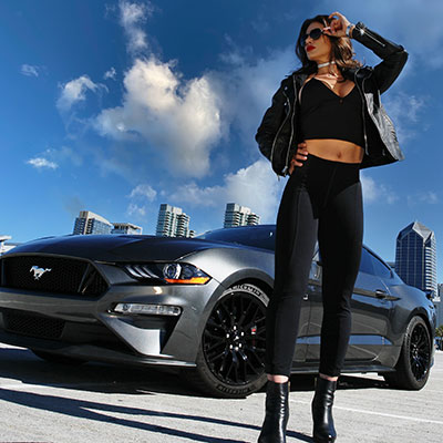 woman standing in front of mustang car